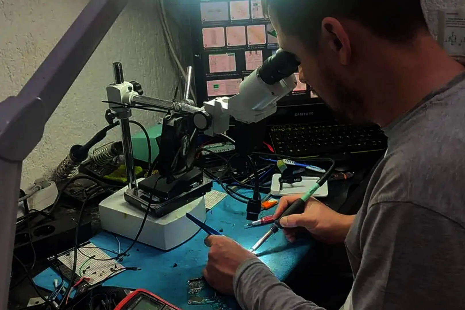 Working under the microscope at the repair bench, soldering iron in hand